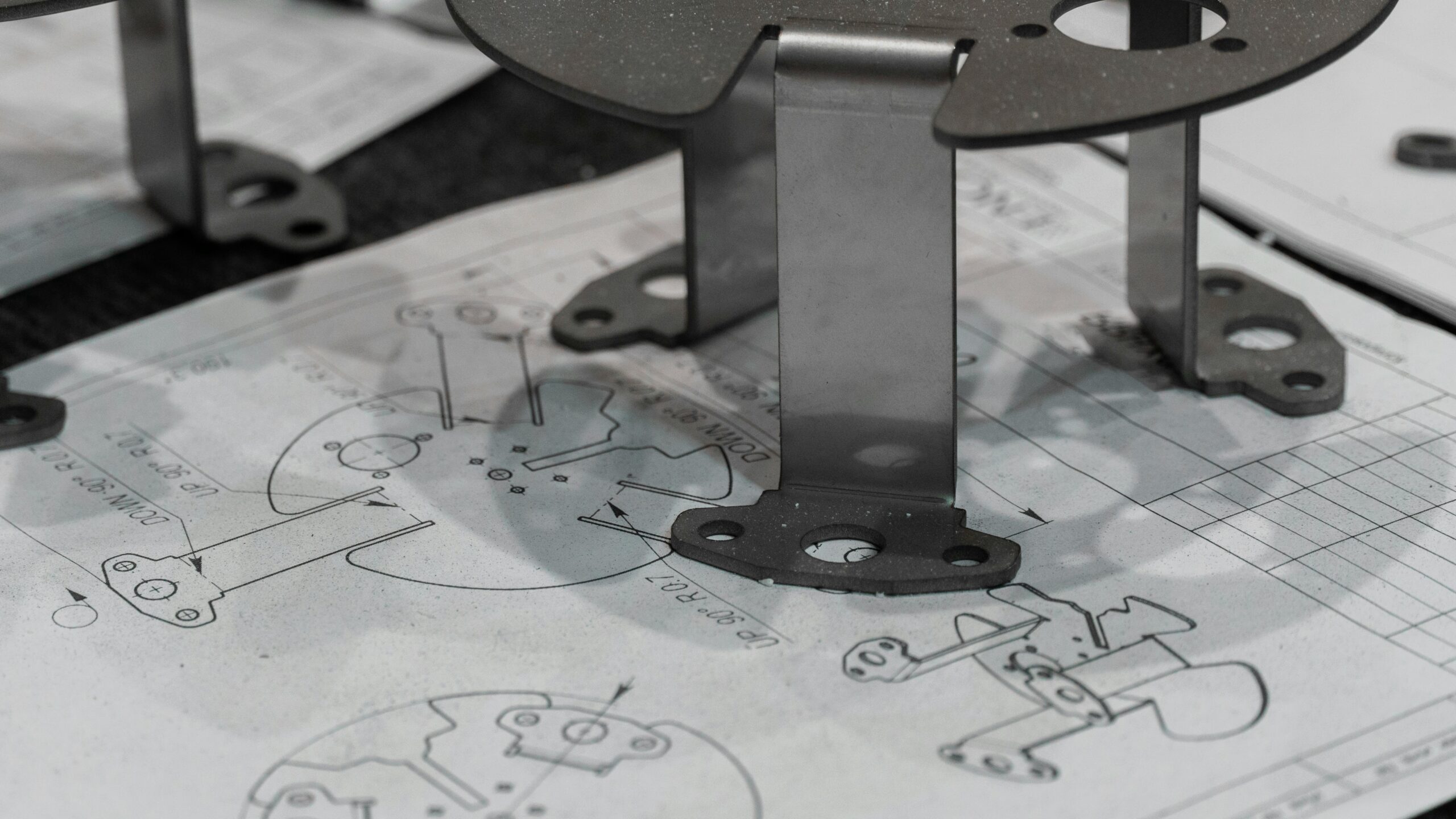 Formed sheet metal brackets resting on a technical drawing