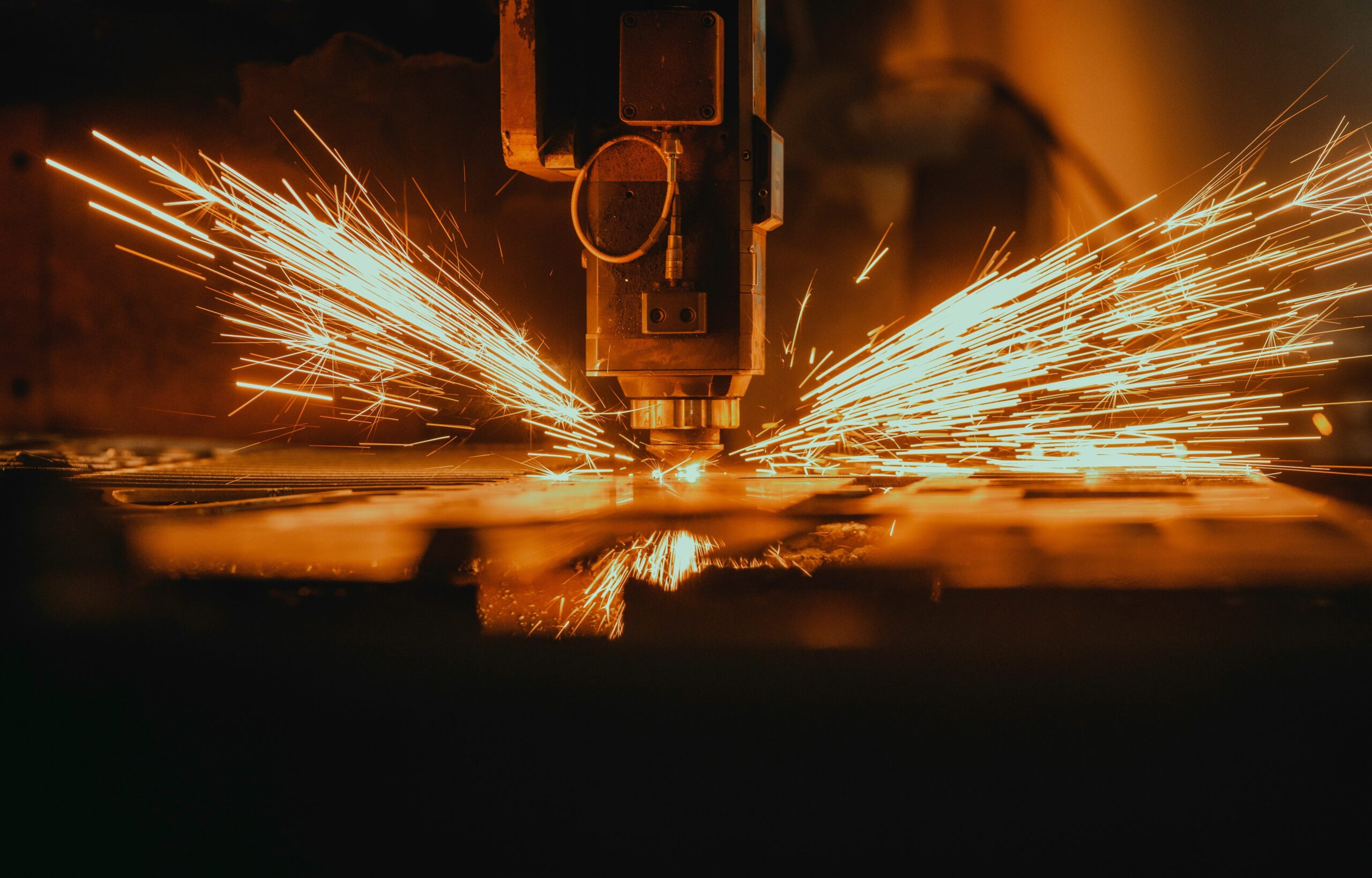 Laser cutting head profiling sheet steel, sparks spraying across the bed